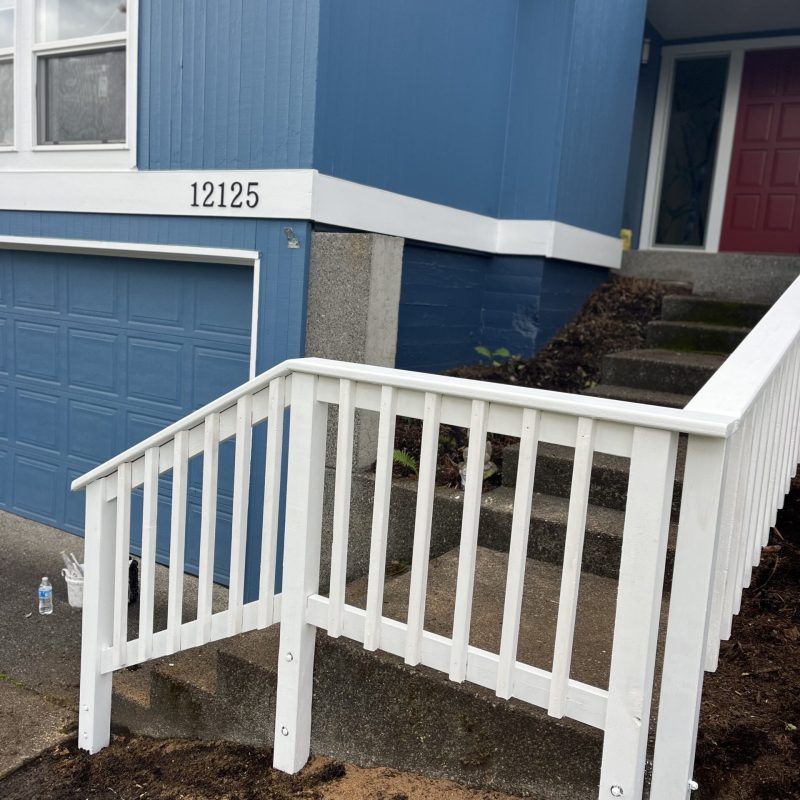 A blue house featuring a white railing and steps, showcasing a charming and inviting exterior design.